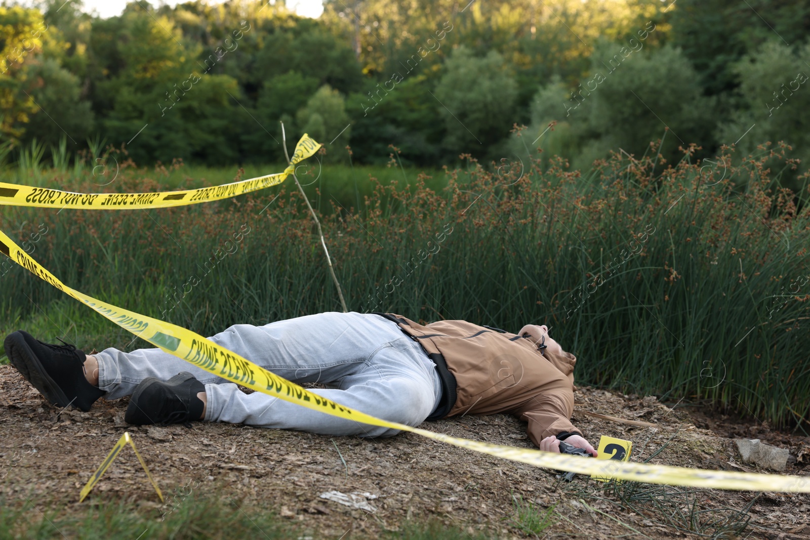 Photo of Forensic expertise. Crime scene with dead man's body and markers outdoors