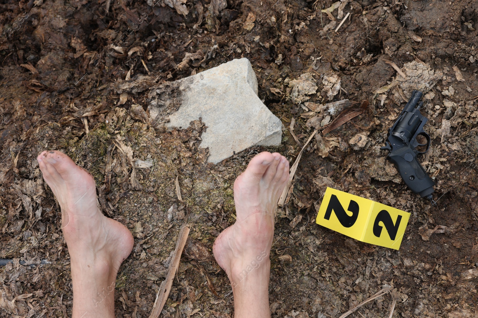 Photo of Forensic expertise. Crime scene with dead man's body, gun and marker outdoors, top view