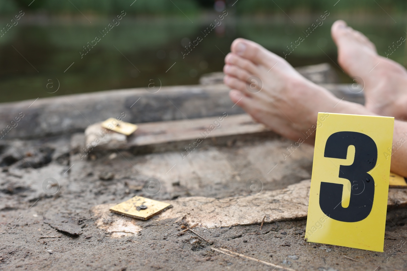 Photo of Forensic expertise. Crime scene with dead man's body and marker near lake outdoors, closeup. Space for text