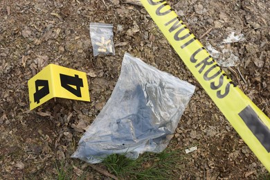 Photo of Forensic expertise. Crime scene with evidence, marker and police tape outdoors, above view