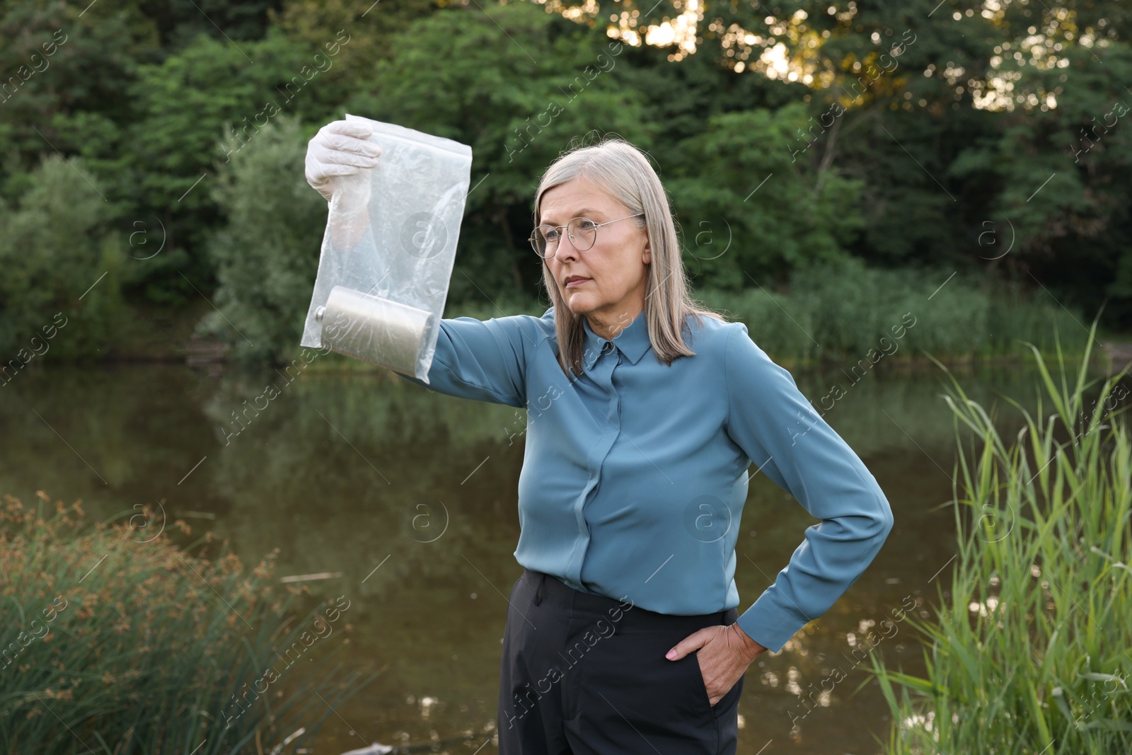 Photo of Forensic expertise. Detective with evidence working near lake outdoors