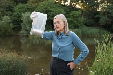 Photo of Forensic expertise. Detective with evidence working near lake outdoors