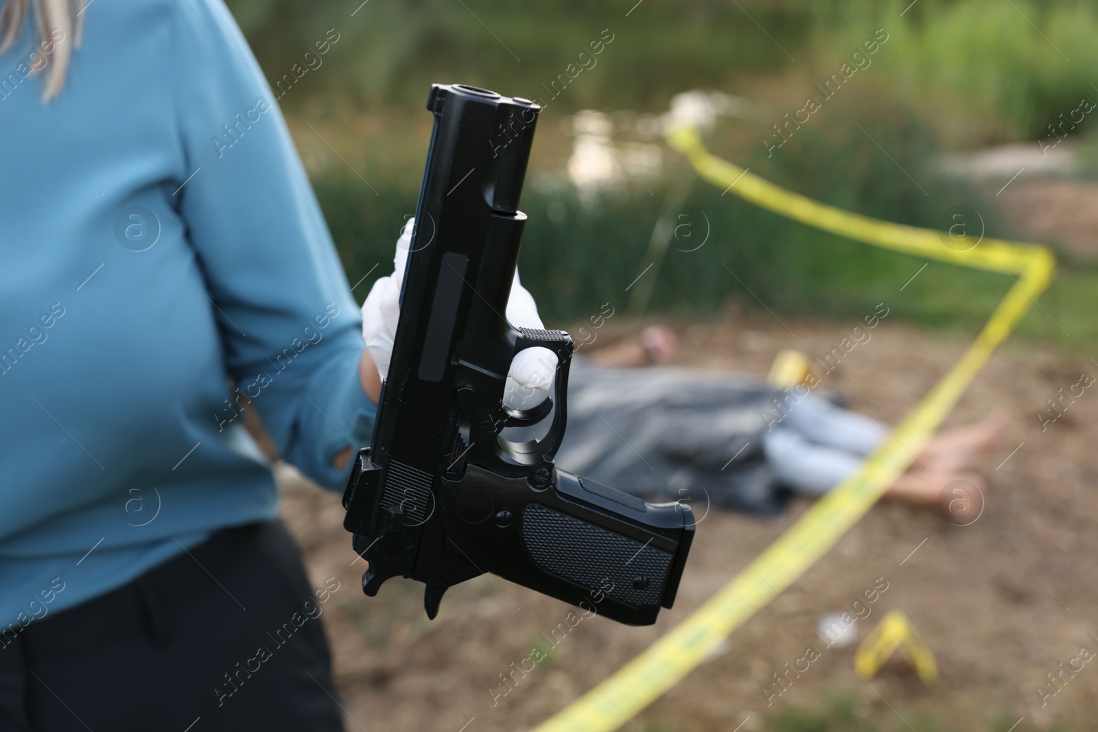 Photo of Forensic expertise. Detective holding evidence working at crime scene with dead man's body outdoors, closeup