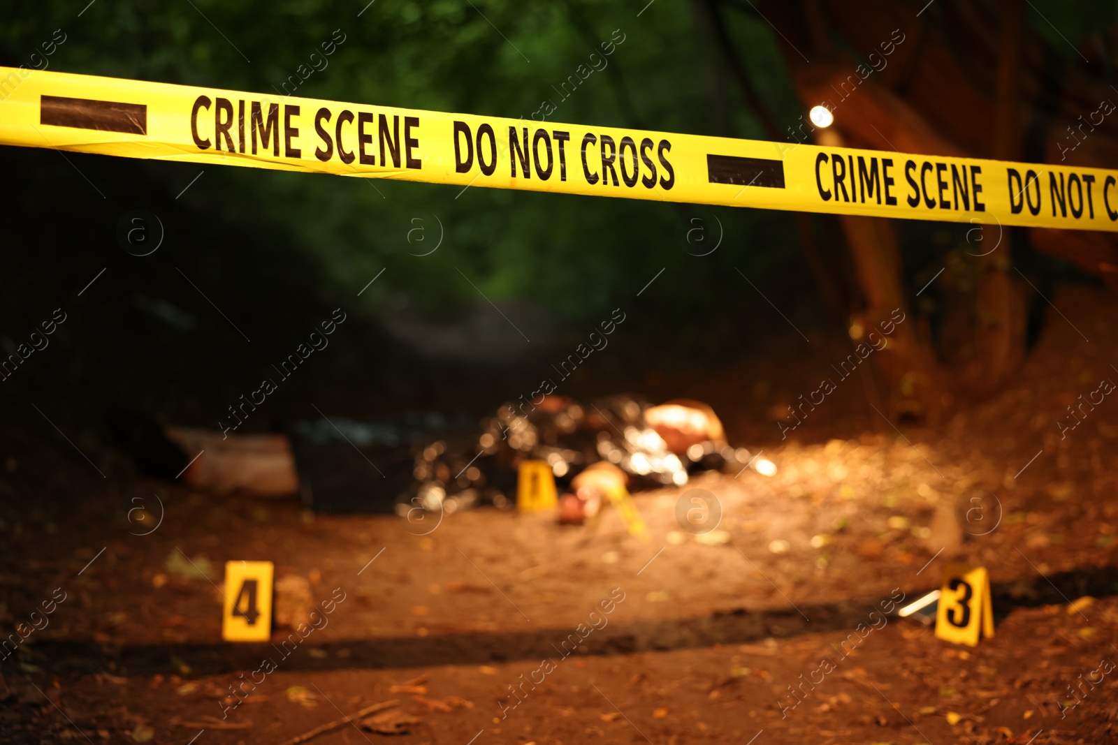 Photo of Forensic expertise. Crime scene with dead man's body and markers outdoors, focus on police tape