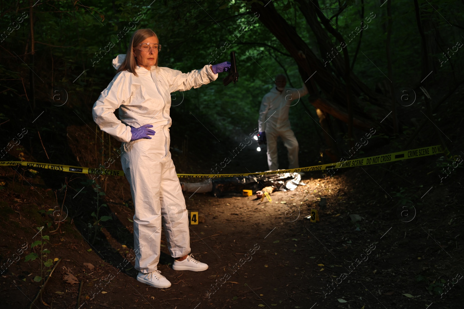 Photo of Forensic experts working at crime scene with dead man's body outdoors