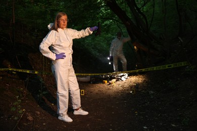 Photo of Forensic experts working at crime scene with dead man's body outdoors