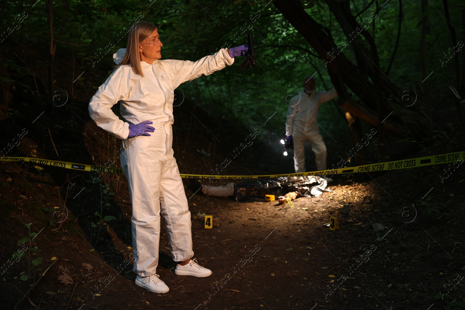 Photo of Forensic experts working at crime scene with dead man's body outdoors