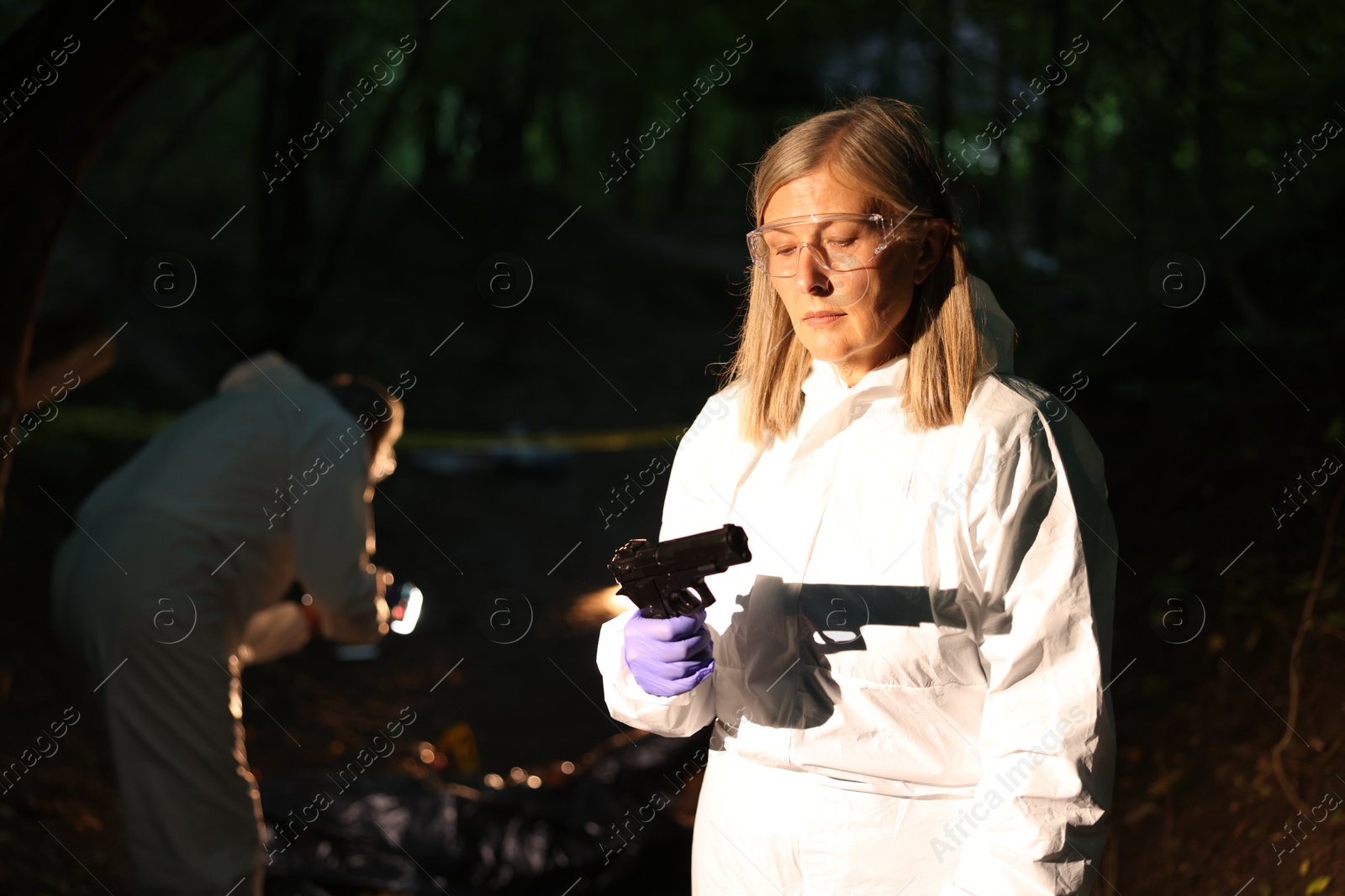 Photo of Forensic experts working at crime scene with dead body outdoors, selective focus