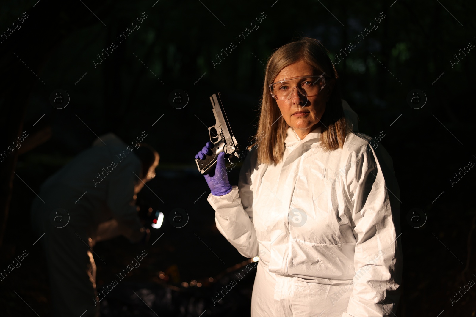 Photo of Forensic experts working at crime scene with dead body outdoors, selective focus