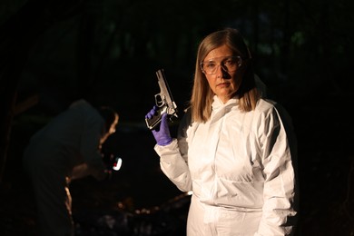 Photo of Forensic experts working at crime scene with dead body outdoors, selective focus