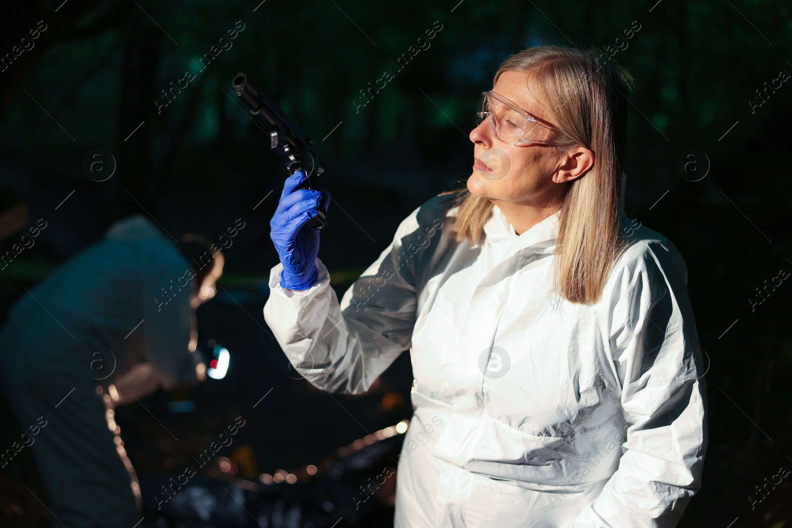 Photo of Forensic experts working at crime scene with dead body outdoors, selective focus