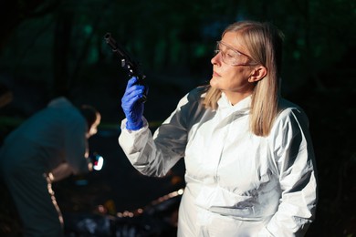 Photo of Forensic experts working at crime scene with dead body outdoors, selective focus