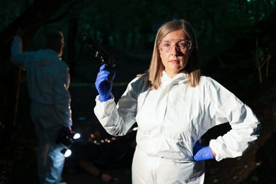 Photo of Forensic experts working at crime scene outdoors, selective focus