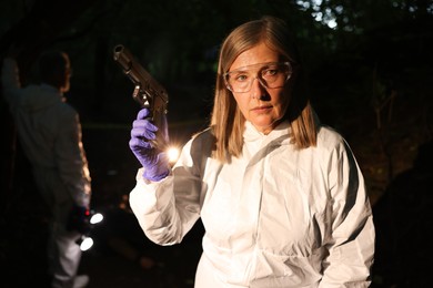 Photo of Forensic experts working at crime scene outdoors, selective focus