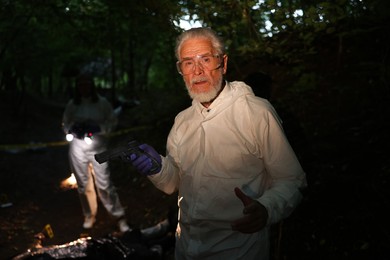 Photo of Forensic experts working at crime scene outdoors, selective focus