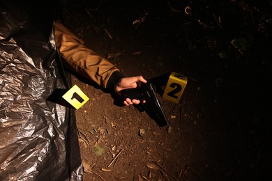 Photo of Forensic expertise. Crime scene with dead man's body, evidence and markers outdoors, above view