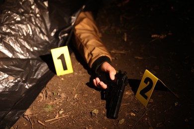 Photo of Forensic expertise. Crime scene with dead man's body, evidence and markers outdoors, closeup