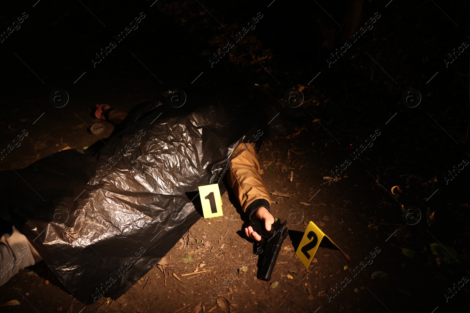 Photo of Forensic expertise. Crime scene with dead man's body, evidence and markers outdoors