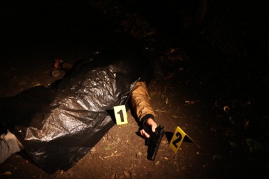 Photo of Forensic expertise. Crime scene with dead man's body, evidence and markers outdoors