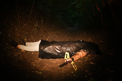 Photo of Forensic expertise. Crime scene with dead man's body and markers outdoors