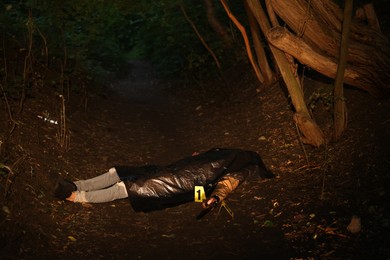 Photo of Forensic expertise. Crime scene with dead man's body and markers outdoors