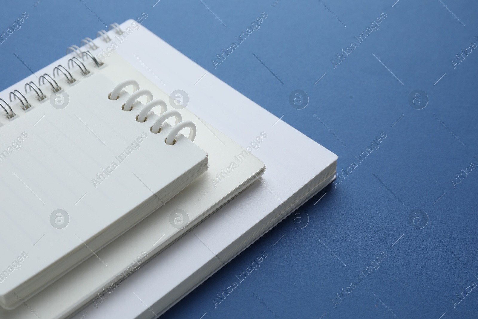 Photo of Three white notebooks on blue background, closeup