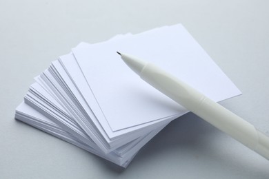 Photo of White pen and note papers on light grey background, closeup