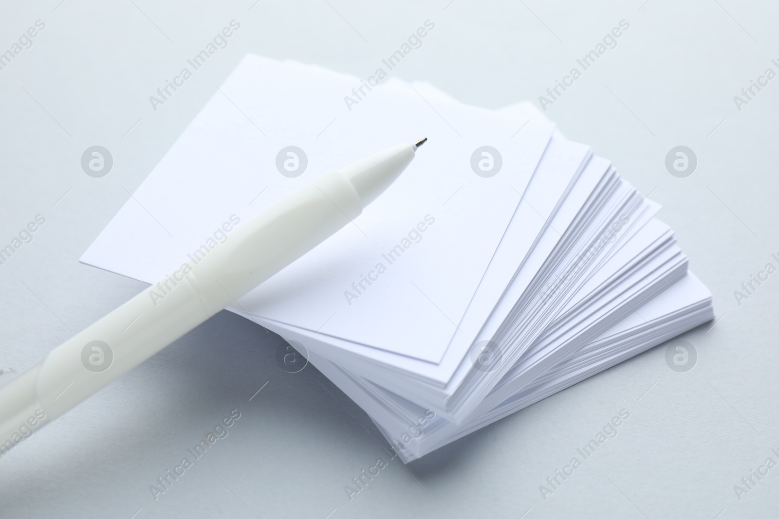 Photo of White pen and note papers on light grey background, closeup