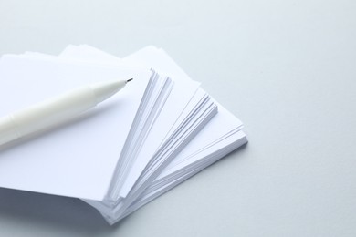Photo of White pen and note papers on light grey background, closeup