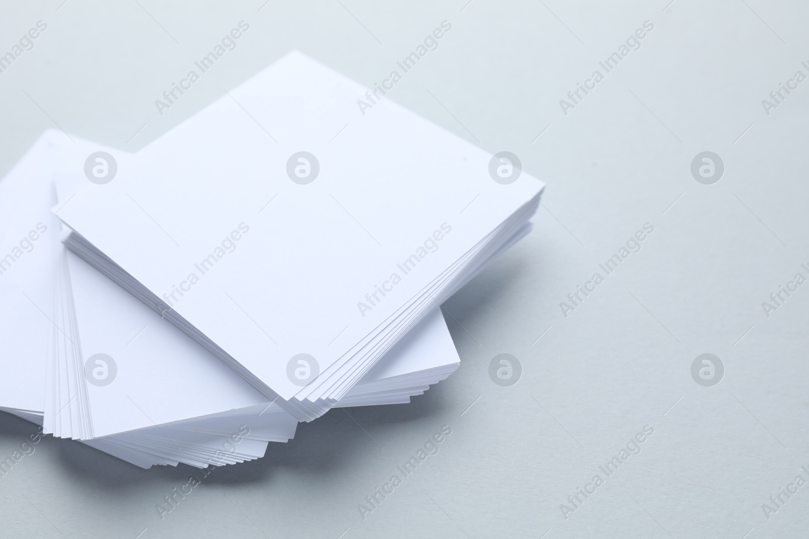 Photo of White note papers on light grey background, closeup. Space for text