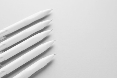 Photo of White pens on light grey background, closeup. Space for text