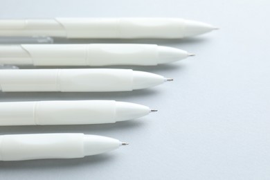Photo of White pens on light grey background, closeup. Space for text