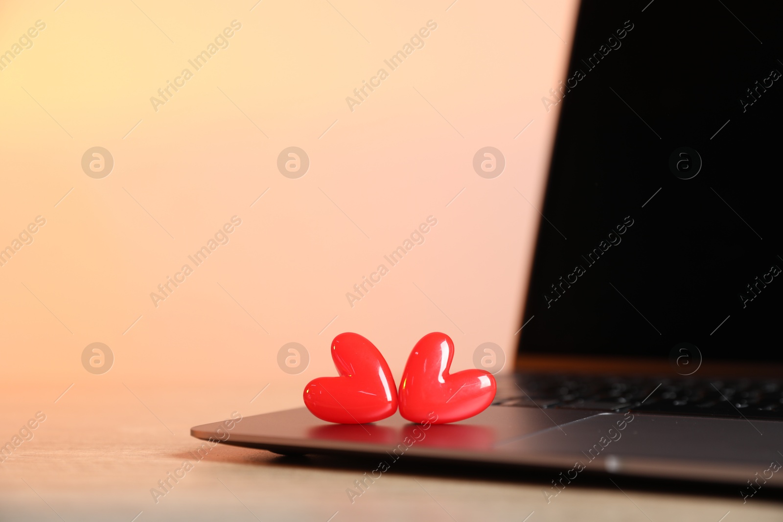 Online dating site. Laptop and red hearts on table, closeup Photo of Online dating site. Laptop and red hearts on table, closeup