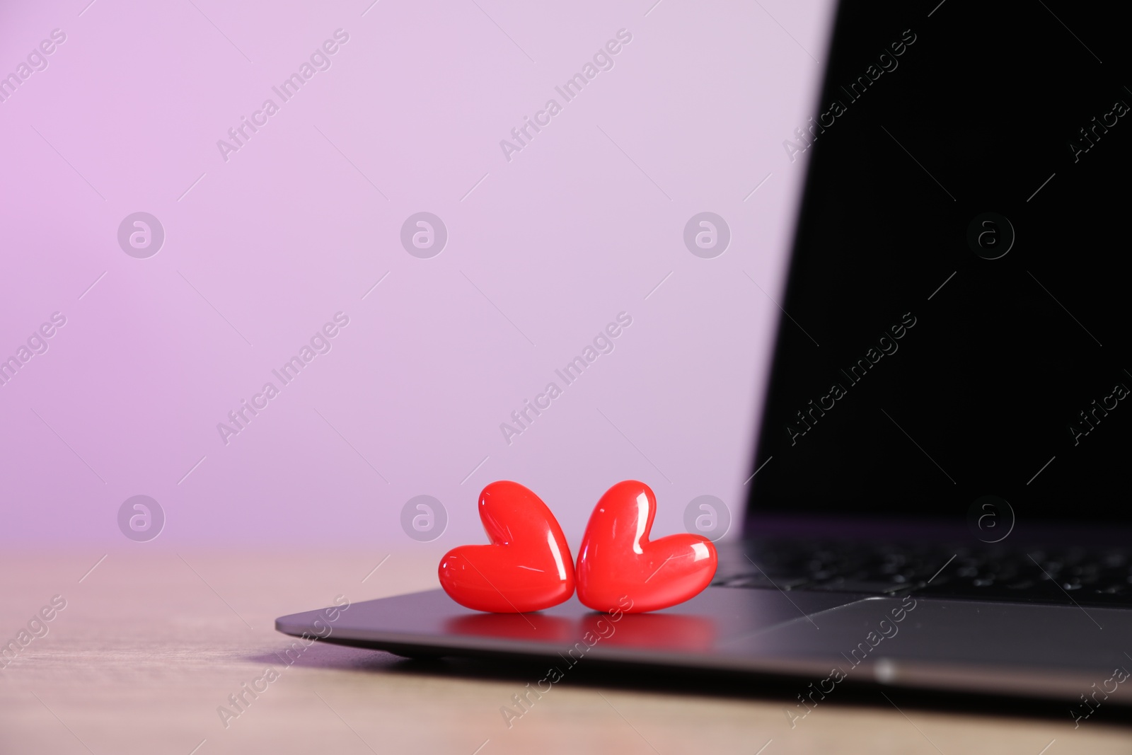 Online dating site. Laptop and red hearts on table, closeup Photo of Online dating site. Laptop and red hearts on table, closeup