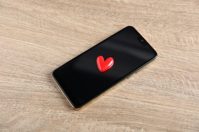 Photo of Online dating site. Smartphone and red heart on wooden table, above view