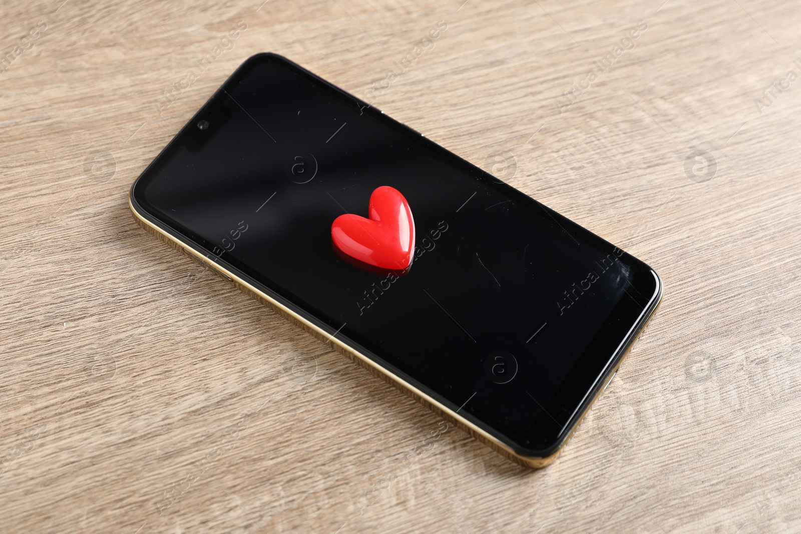 Photo of Online dating site. Smartphone and red heart on wooden table, above view