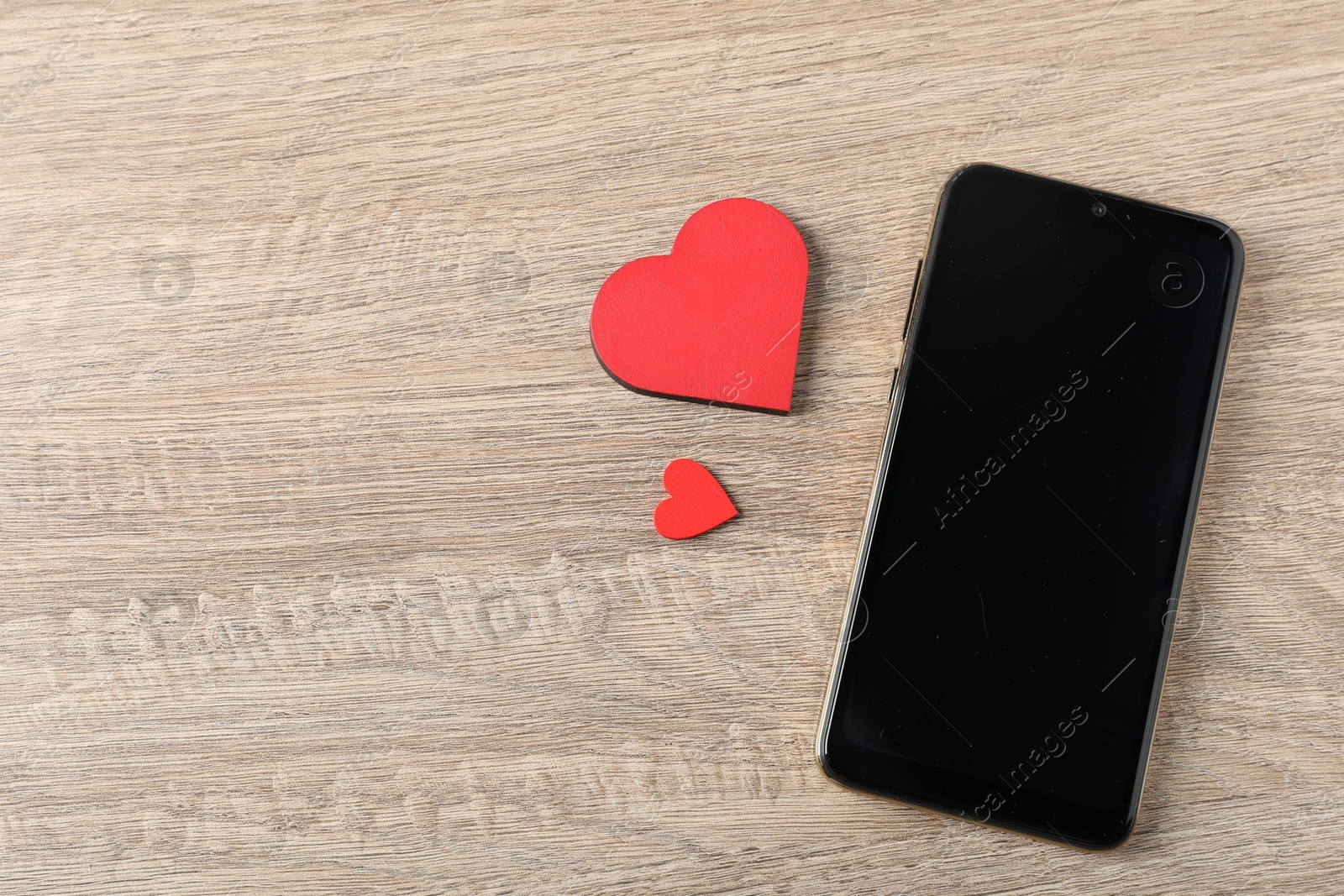 Online dating site. Smartphone and red hearts on wooden table, flat lay. Space for text Photo of Online dating site. Smartphone and red hearts on wooden table, flat lay. Space for text