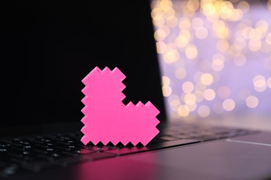 Photo of Online dating site. Pink heart on laptop against blurred lights, closeup. Bokeh effect