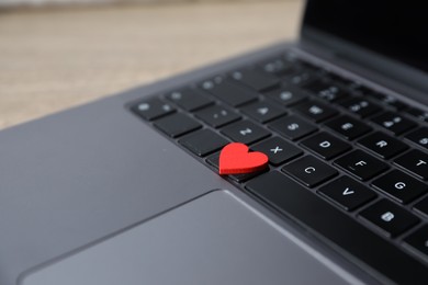 Photo of Online dating site. Red heart and laptop on table, closeup