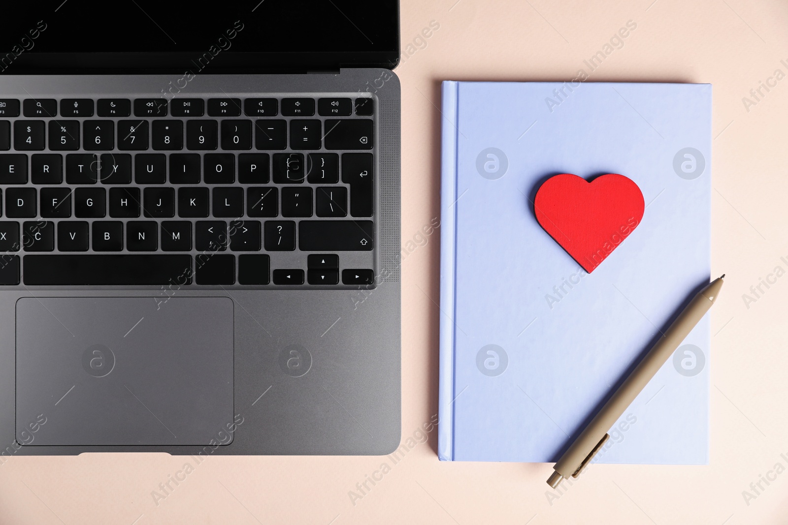 Photo of Online dating site. Laptop, notebook, red heart and pen on beige background, flat lay