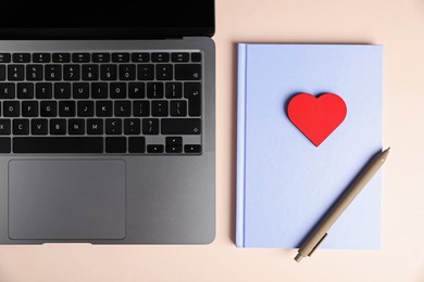 Photo of Online dating site. Laptop, notebook, red heart and pen on beige background, flat lay