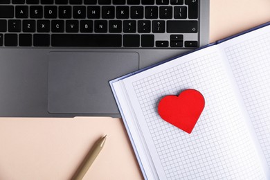 Photo of Online dating site. Laptop, notebook, red heart and pen on beige background, flat lay