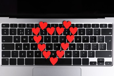 Photo of Online dating site. Many red hearts on laptop, top view