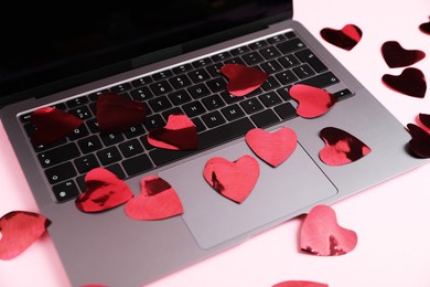 Photo of Online dating site. Many red hearts and laptop on pink background, closeup