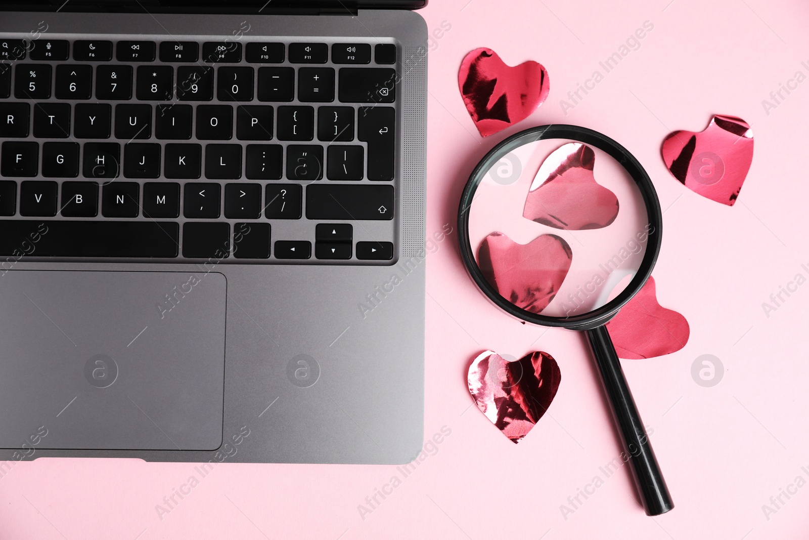 Online dating site. Many red hearts, magnifying glass and laptop on pink background, flat lay Photo of Online dating site. Many red hearts, magnifying glass and laptop on pink background, flat lay