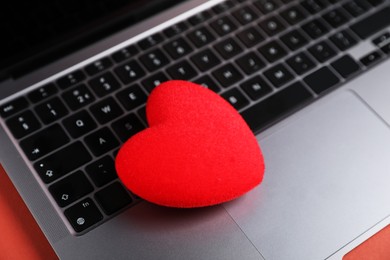 Photo of Online dating site. Red heart and laptop on color background, closeup