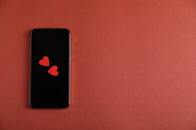 Photo of Online dating site. Smartphone and hearts on red-brown background, top view. Space for text