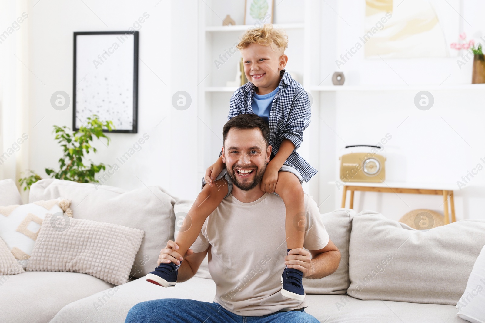 Photo of Happy father and his son spending time together on sofa at home. Family