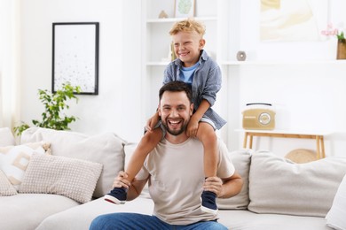 Photo of Happy father and his son spending time together on sofa at home. Family