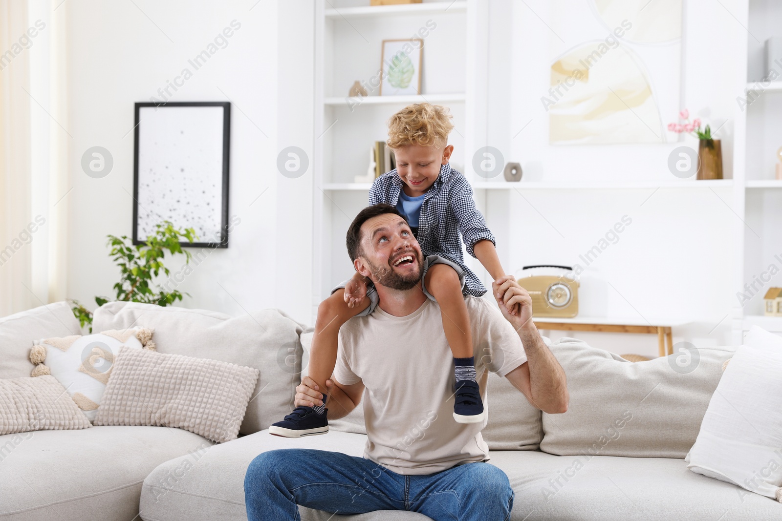 Photo of Happy father and his son spending time together on sofa at home. Family